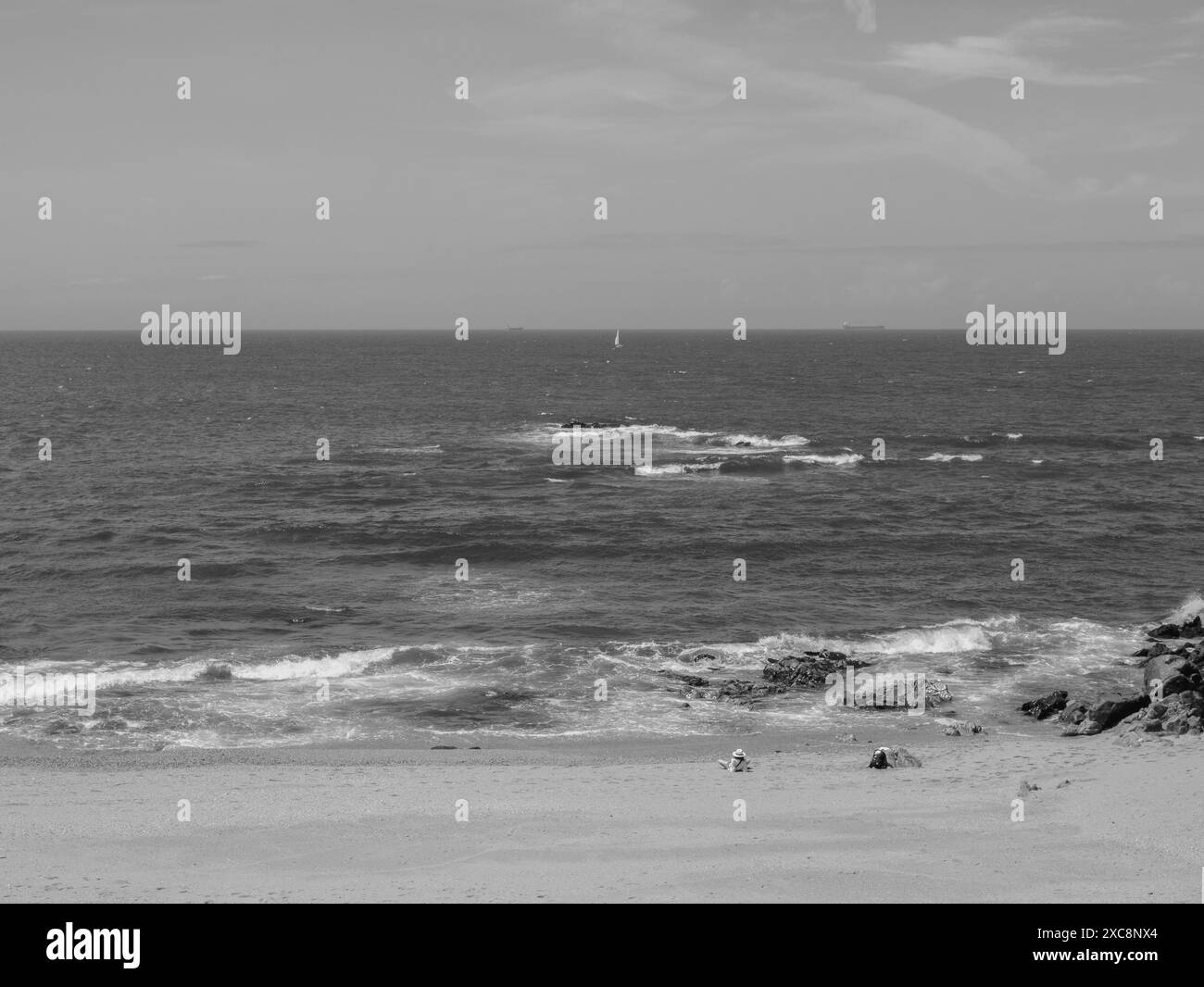 vista sul retro in bianco e nero della silhouette anonima che si stende sulla spiaggia e guarda la vista dell'oceano atlantico Foto Stock