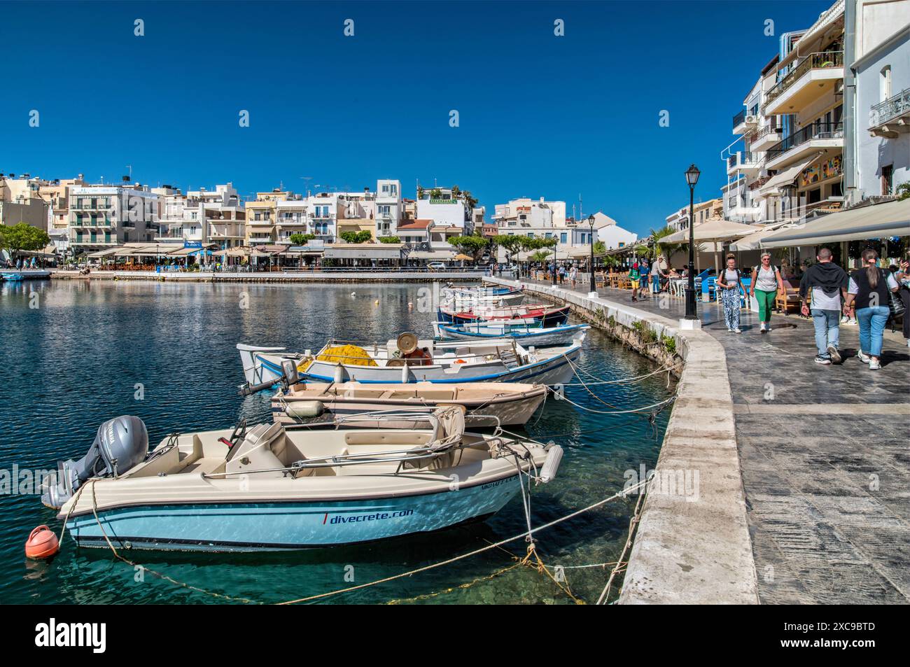 Barche, passanti alla banchina presso la laguna del lago Voulismeni nella città di Agios Nikolaos, Creta orientale, Grecia Foto Stock