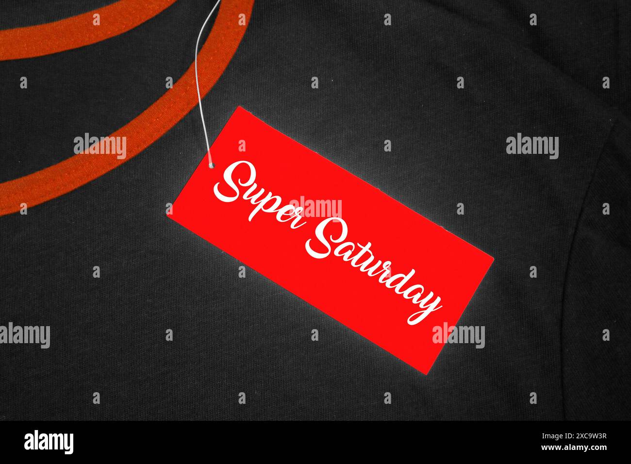 Etichetta rossa su una t-shirt grigia e arancione con "Super Saturday" scritta in bianco. Foto Stock