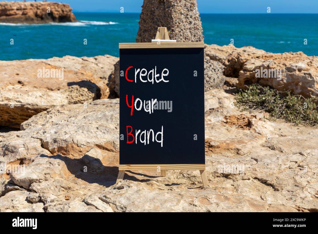 CYB Crea il simbolo del tuo marchio. Parole concettuali CYB Crea il tuo marchio su una bellissima lavagna gialla. Bellissimo sfondo blu cielo in pietra. Business CY Foto Stock
