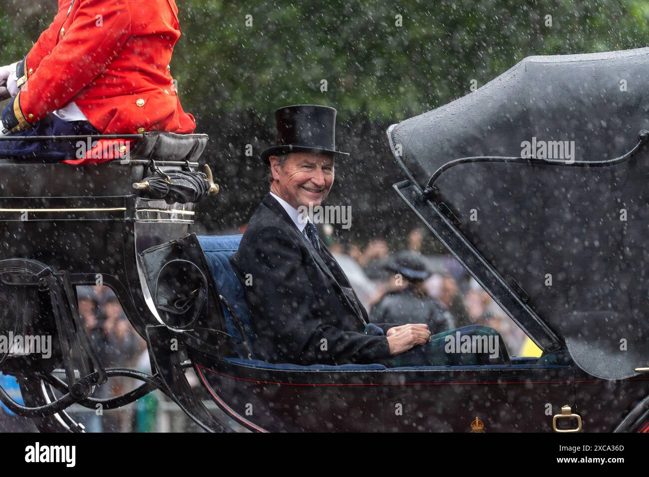 Sir Timothy Laurence che cavalca nella sezione aperta di una carrozza trainata da cavalli durante un forte temporale a Trooping the Colour 2024, bagnandosi Foto Stock