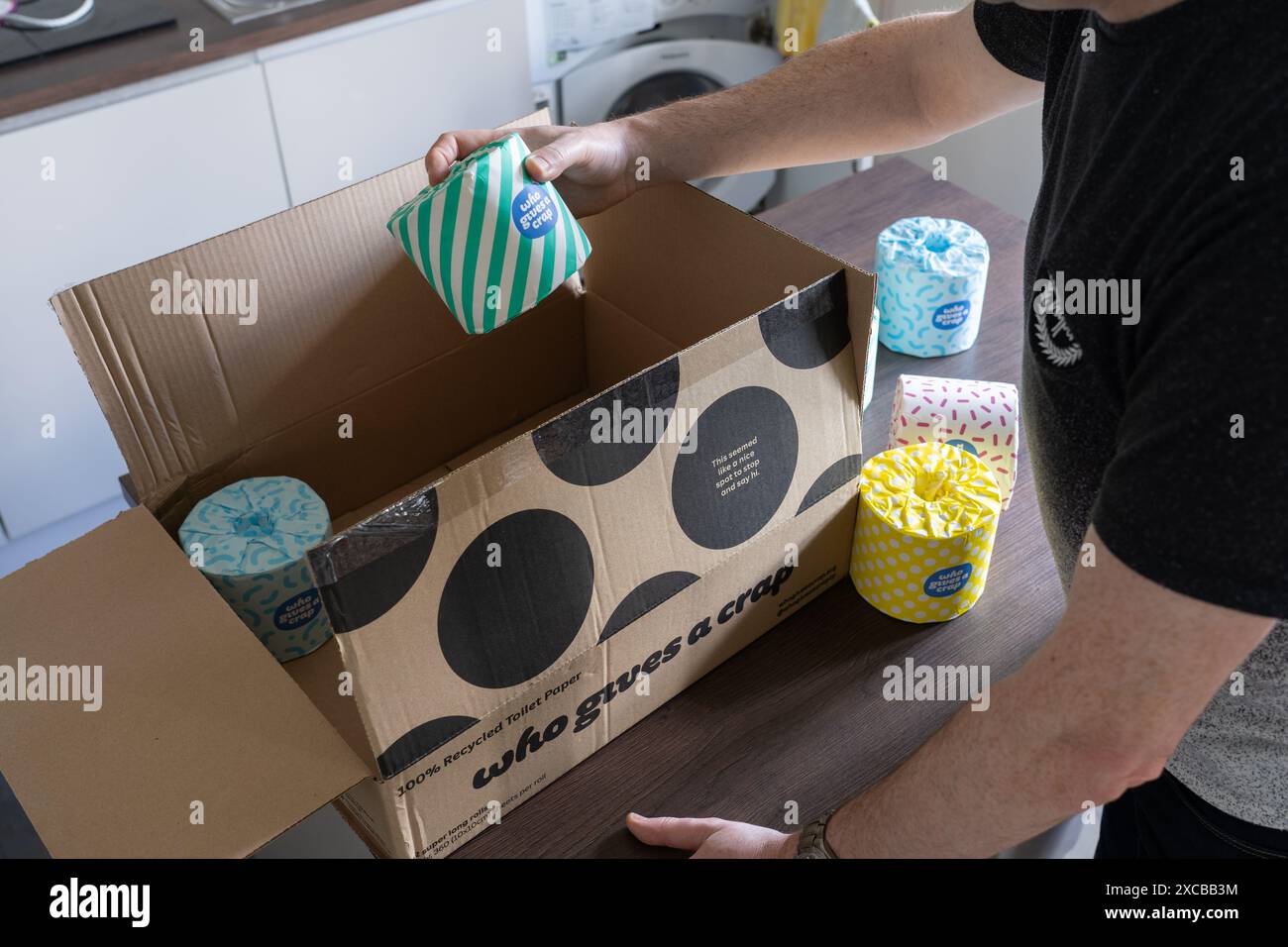 Uomo che porta via un rotolo di carta igienica avvolto in carta da regalo con il logo dell'azienda. Concetto: Carta igienica sostenibile Foto Stock