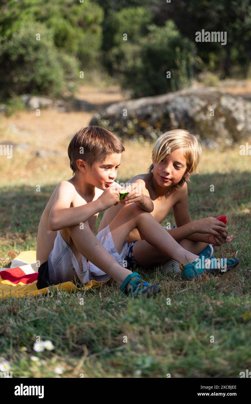 Due bambini caucasici che mangiano anguria in una giornata estiva in natura Foto Stock