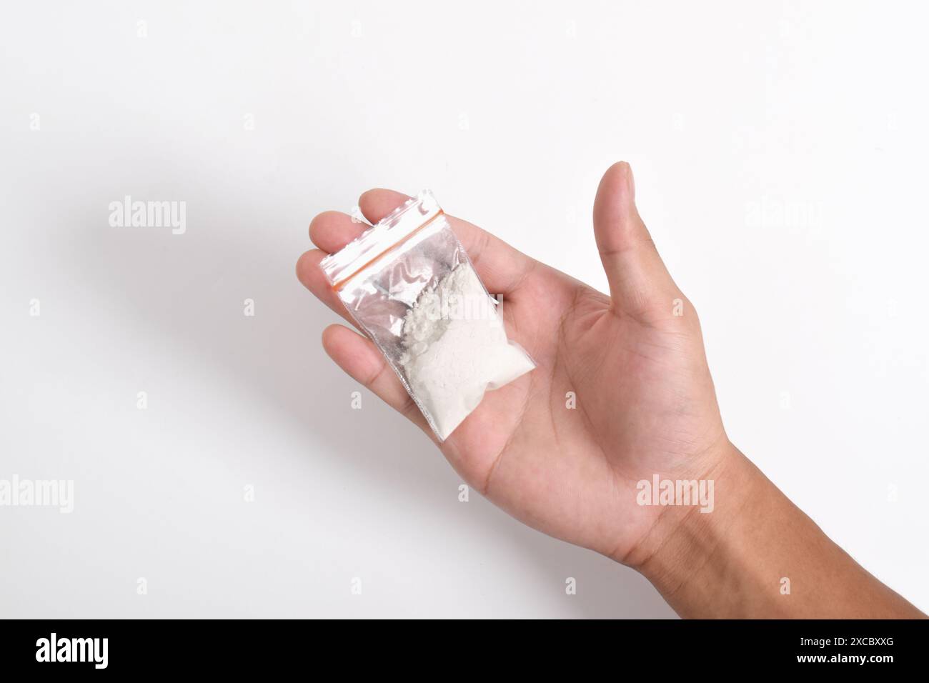 La mano fornisce cocaina in un contenitore di plastica isolato su sfondo bianco. Illustrazione di sostanze stupefacenti illegali, narcotici Foto Stock