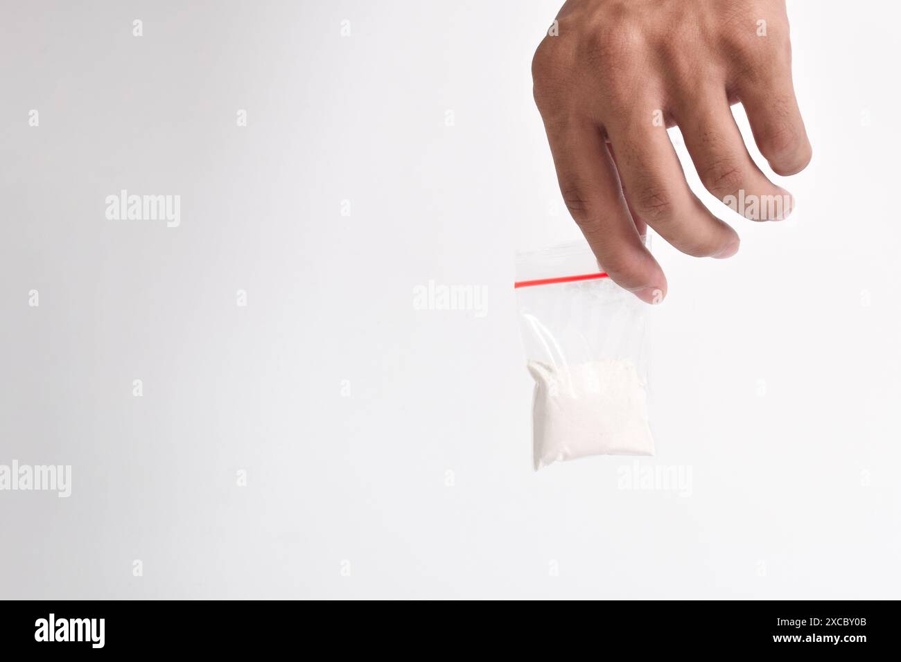 Mano che tiene la cocaina in un pacchetto di plastica isolato su sfondo bianco. illustrazione di sostanze stupefacenti illegali, narcotici Foto Stock