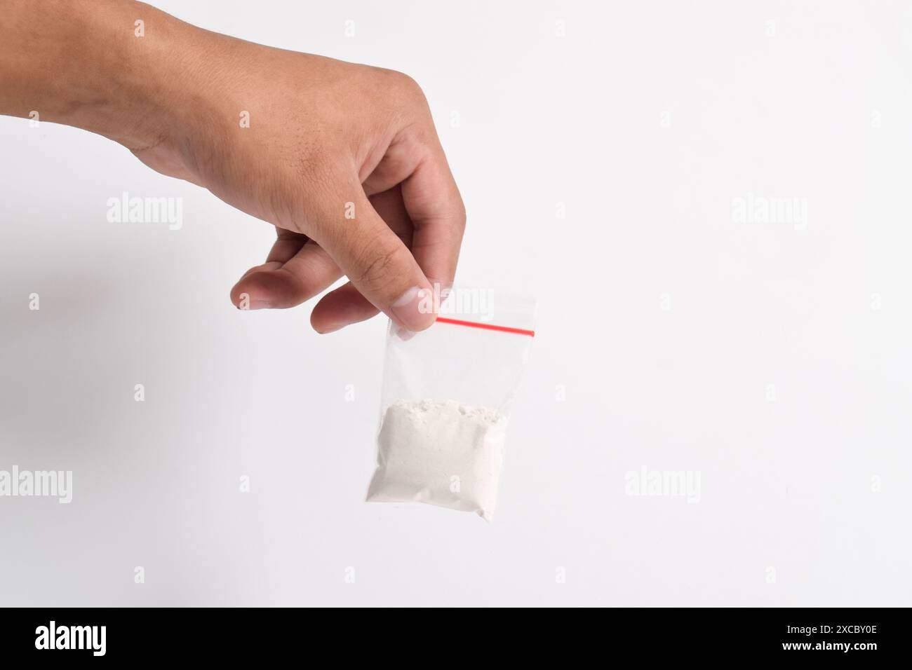 Mano che tiene la cocaina in un pacchetto di plastica isolato su sfondo bianco. illustrazione di sostanze stupefacenti illegali, narcotici Foto Stock