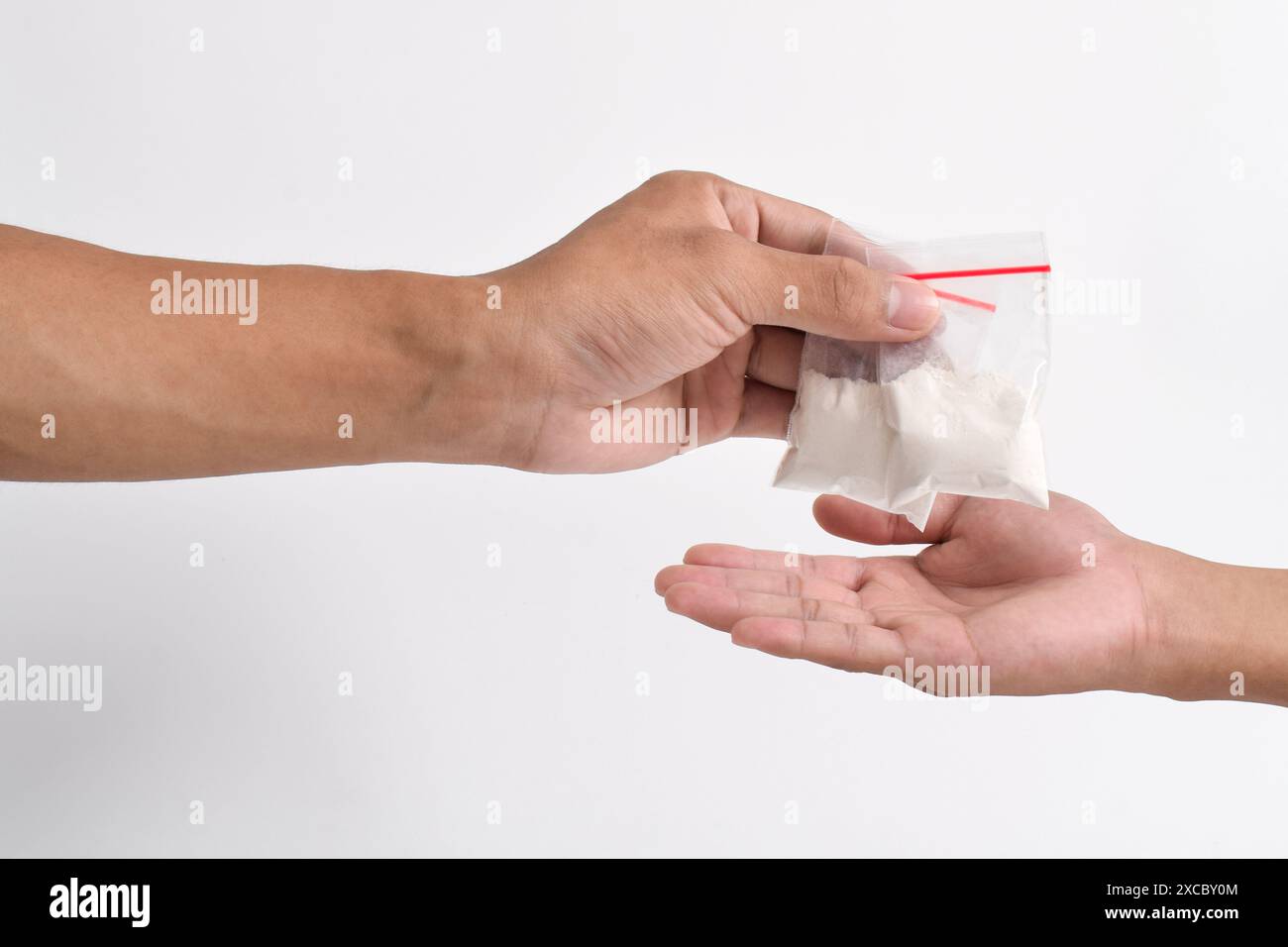 La mano fornisce cocaina in un contenitore di plastica isolato su sfondo bianco. Illustrazione di sostanze stupefacenti illegali, narcotici Foto Stock