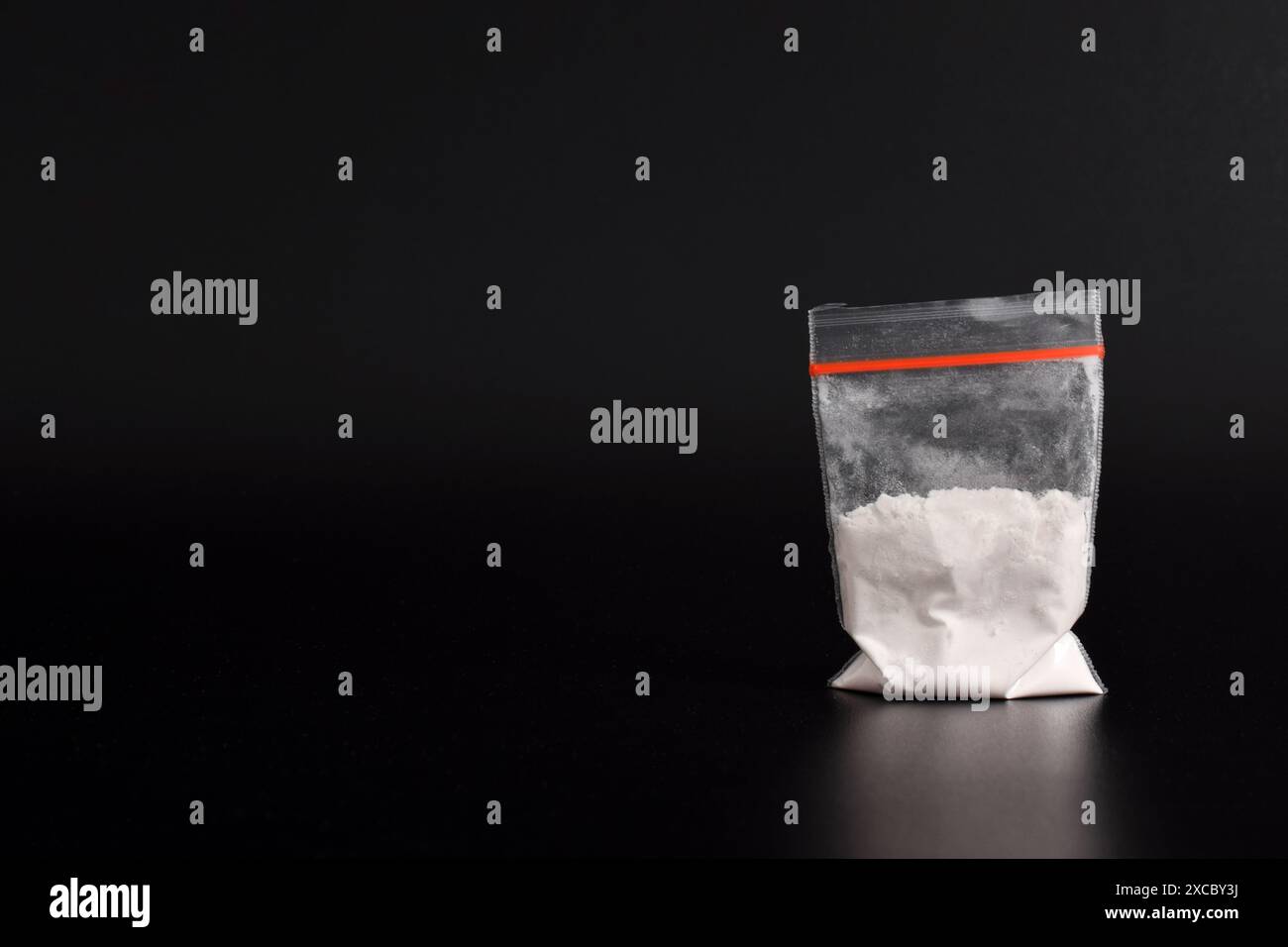 Cocaina in confezione di plastica isolata su sfondo nero. illustrazione di sostanze stupefacenti illegali, narcotici Foto Stock