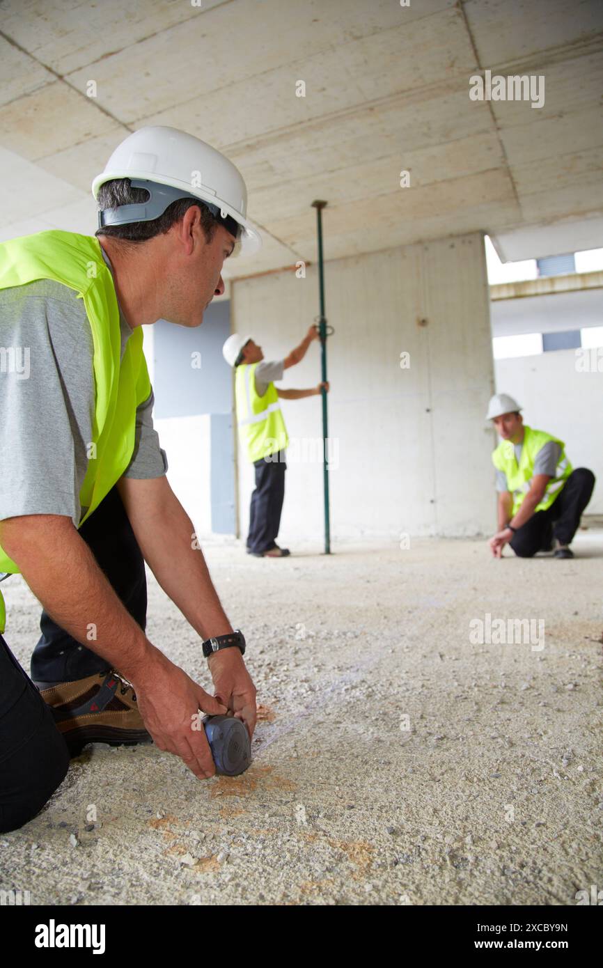 Lavoratori con dispositivi di protezione individuale, DPI, linee guida per la marcatura per la costruzione di pareti interne, tracciatore di linee, costruzione di alloggiamenti, controbattitore Foto Stock
