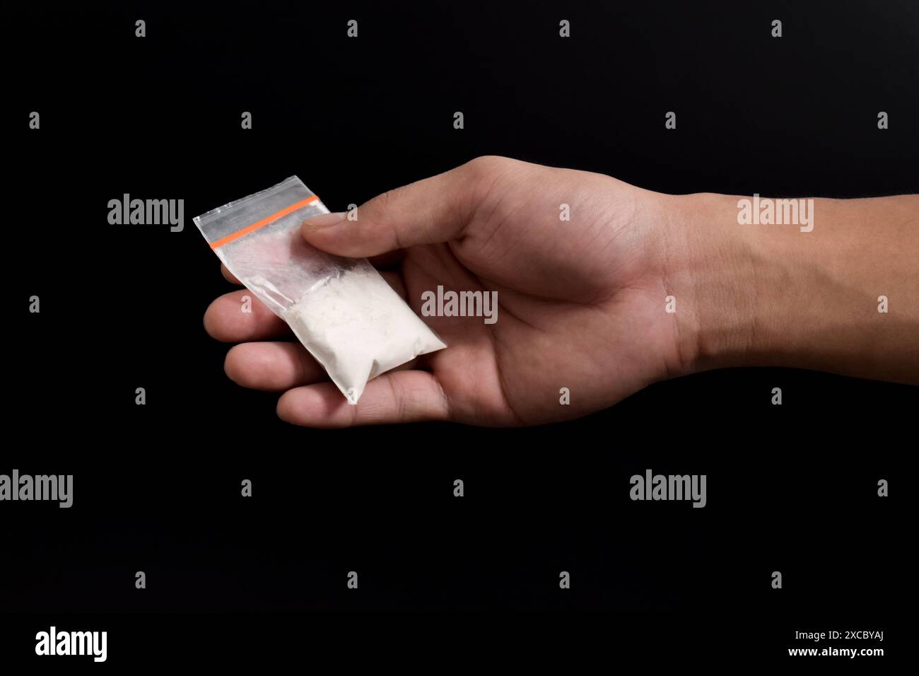 Cocaina a mano in un contenitore di plastica isolato su sfondo nero. Illustrazione di sostanze stupefacenti illegali, narcotici Foto Stock