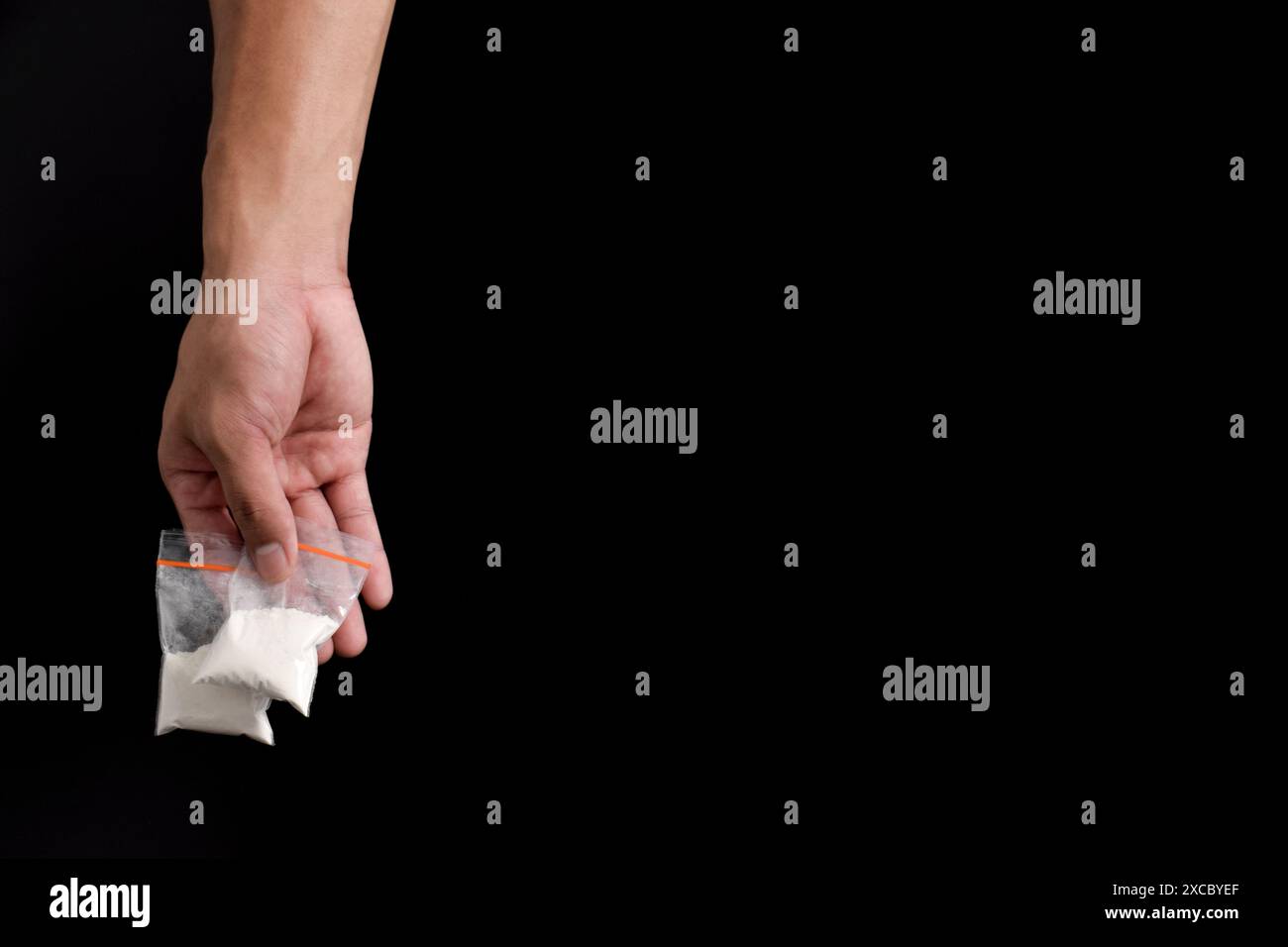 Cocaina a mano in un contenitore di plastica isolato su sfondo nero. Illustrazione di sostanze stupefacenti illegali, narcotici Foto Stock