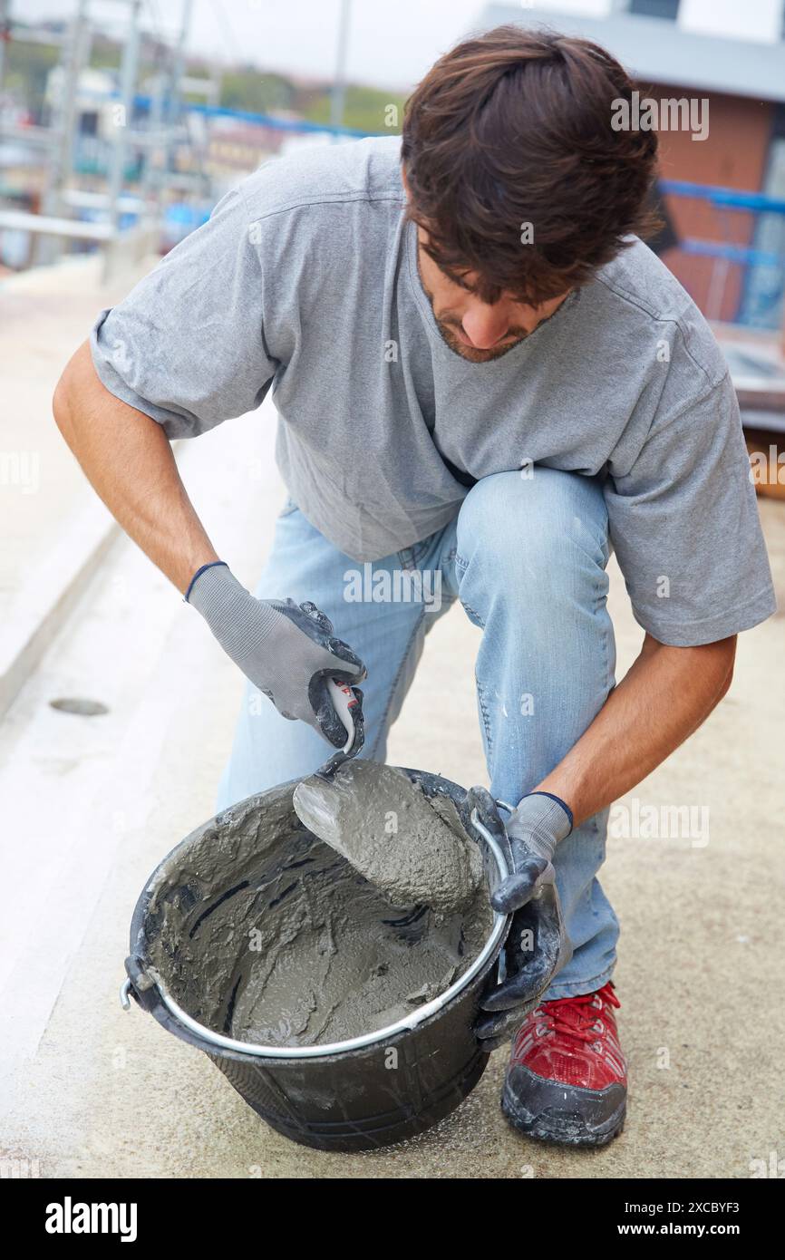 Muratore rendendo malta cementizia. Costruzione di edilizia residenziale. Donostia. San Sebastian. Gipuzkoa. Paese basco. Spagna. Foto Stock