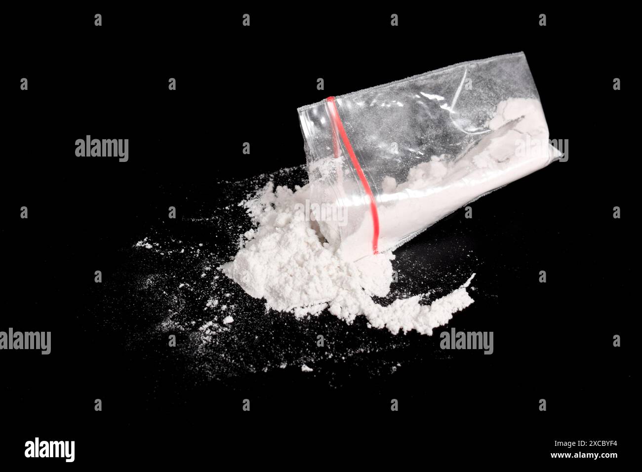Cocaina in confezione di plastica spolverata su sfondo nero. Illustrazione di sostanze stupefacenti illegali, narcotici Foto Stock