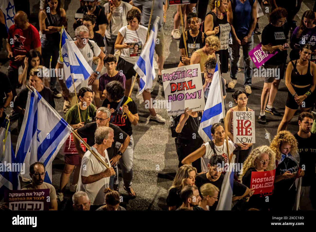 Tel Aviv, Israele. 15 giugno 2024. I manifestanti tengono i cartelli che chiedono un accordo con Hamas durante una manifestazione a Tel Aviv, sabato 15 giugno 2024. Decine di migliaia di manifestanti si sono riuniti in decine di luoghi in Israele sabato sera, chiedendo di porre fine alla guerra a Gaza per un accordo di ostaggi e nuove elezioni poche ore dopo la notizia di otto soldati israeliani uccisi in un'esplosione a Rafah sabato mattina. Foto di Eyal Warshavsky. Crediti: Eyal Warshavsky/Alamy Live News Foto Stock