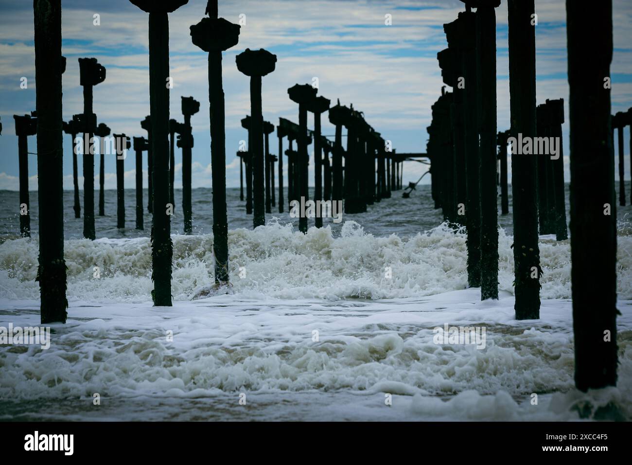 Le onde colpiscono pilastri di legno su una spiaggia. Kerala, India Foto Stock