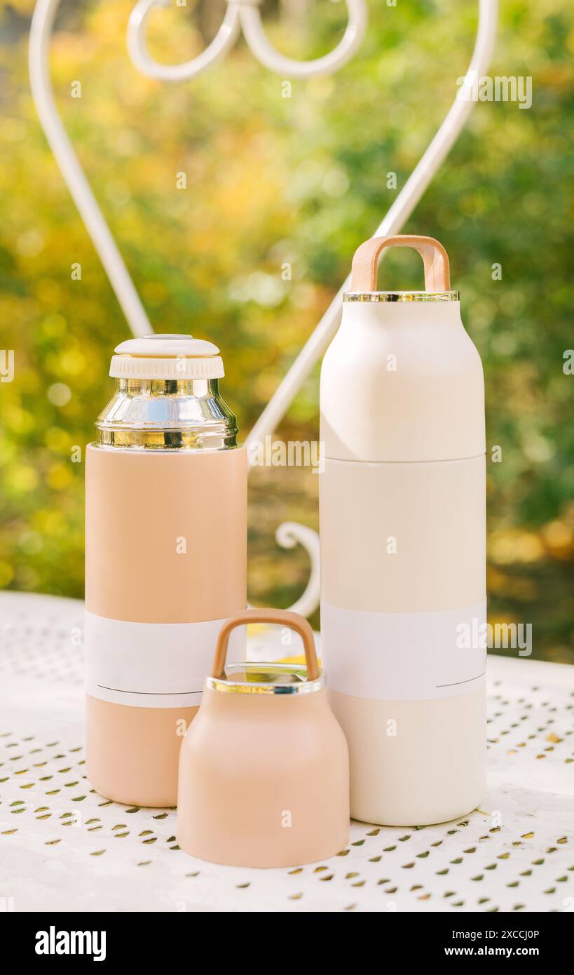 Moderno termos in acciaio inox e plastica con tazza in parco in autunno. termos sottovuoto. Concetto per attività all'aperto, bevande calde, escursioni, viaggi. Foto Stock