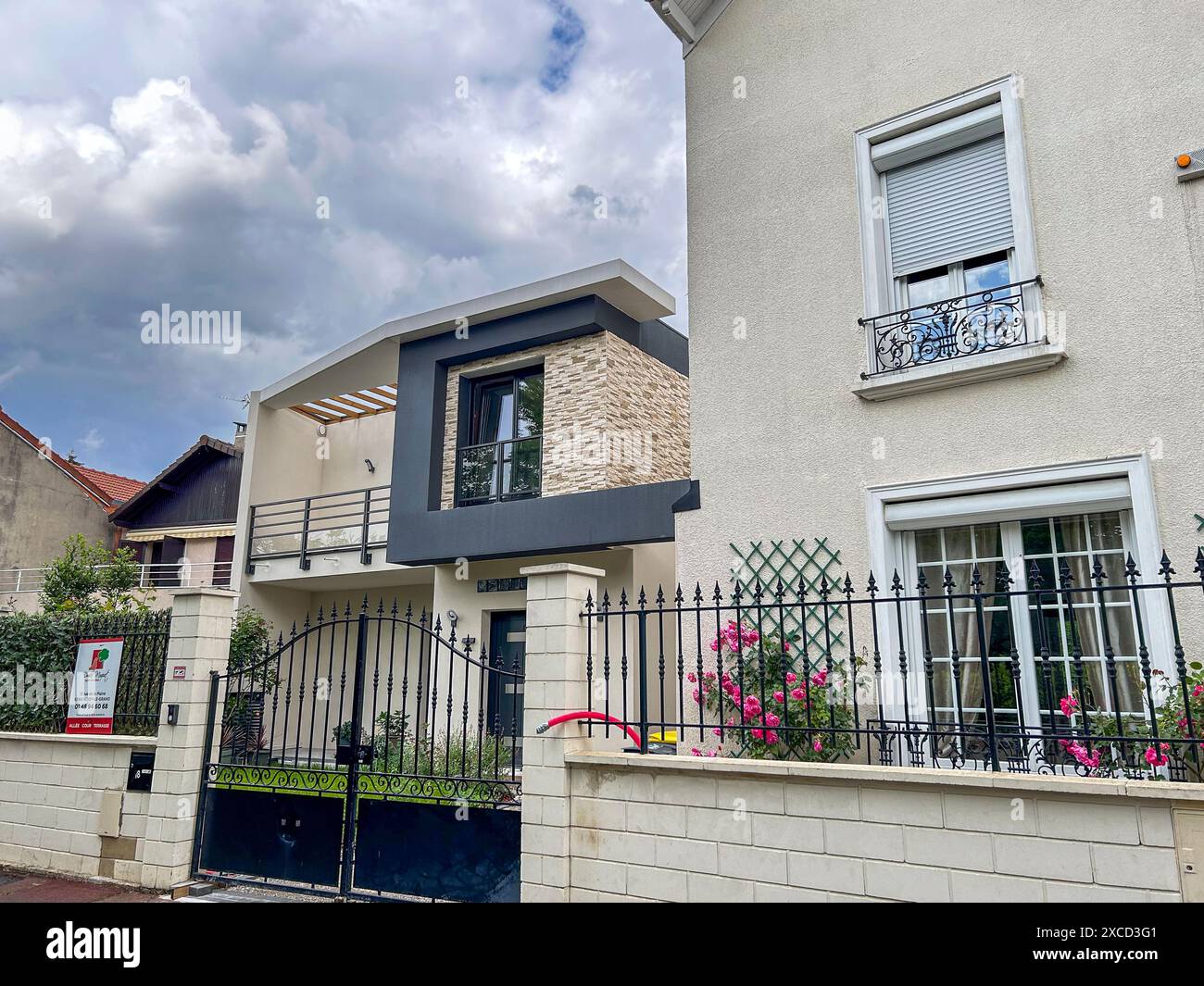 La casa nell'immagine mostra uno stile architettonico moderno con un mix di materiali, come pietra e stucco. I quartieri orientali a contrasto Foto Stock