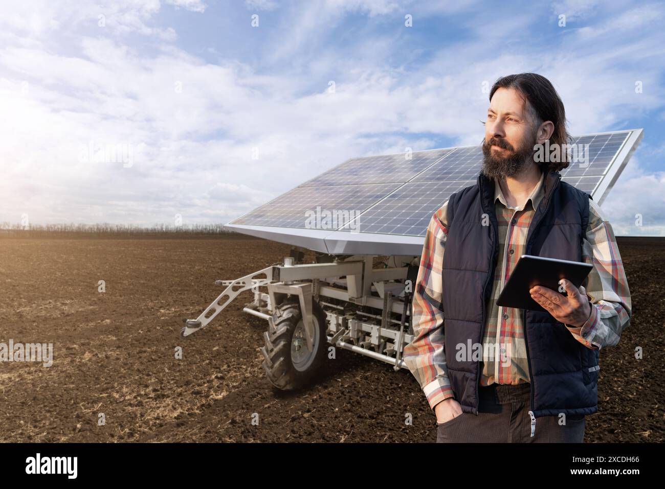 L'agricoltore controlla macchine agricole autonome alimentate da energia solare. Foto Stock