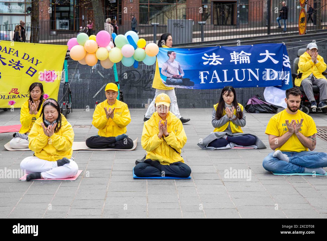 Falung Gong aderenti che fanno il quinto esercizio in posizione di loto seduto nel distretto di Kamppi a Helsinki, Finlandia Foto Stock
