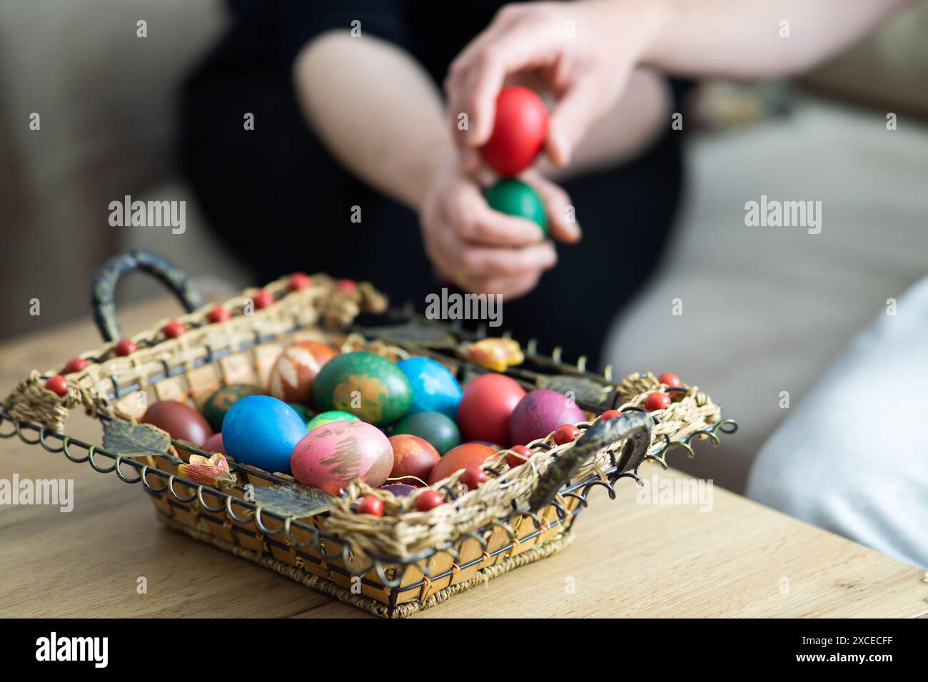 spillatura delle uova di pasqua, spillatura delle uova di mamma e figlio accanto al cestino con uova di pasqua, messa a fuoco selettiva, primo piano delle mani che toccano le uova Foto Stock