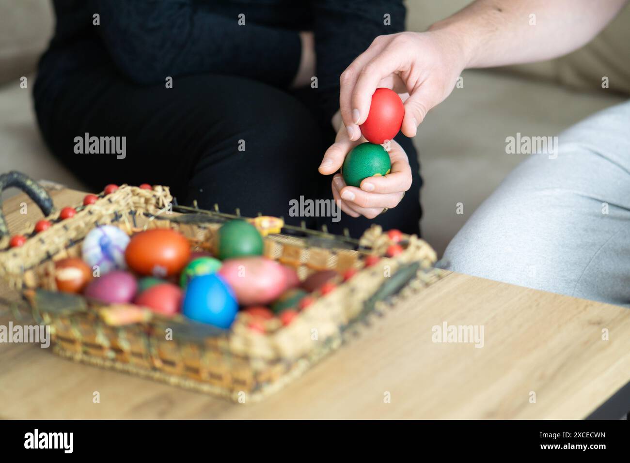 spillatura delle uova di pasqua, spillatura delle uova di mamma e figlio accanto al cestino con uova di pasqua, messa a fuoco selettiva, primo piano delle mani che toccano le uova Foto Stock