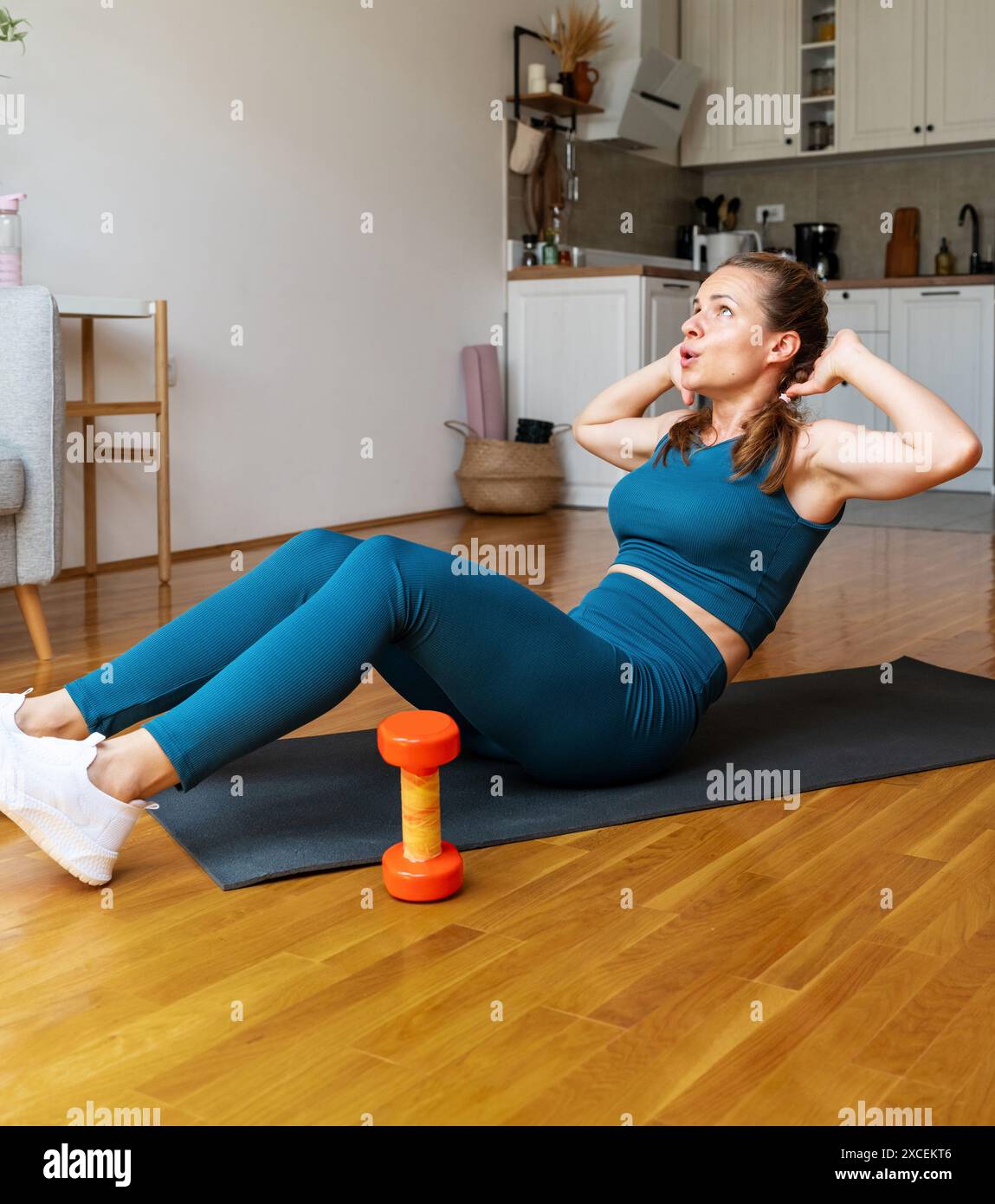 Atletica giovane donna in abbigliamento sportivo che fa esercizio abs a casa. Cura del corpo e stile di vita sano. Foto Stock