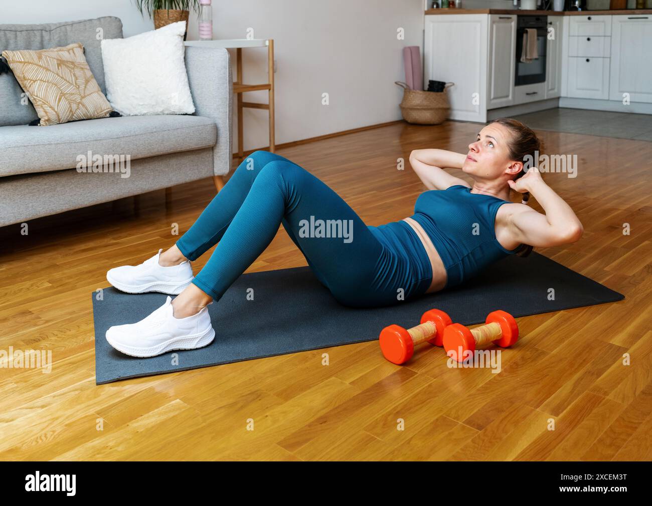 Donna in abbigliamento sportivo che fa esercizio fisico con abs a casa. Allenamento AB. Foto Stock