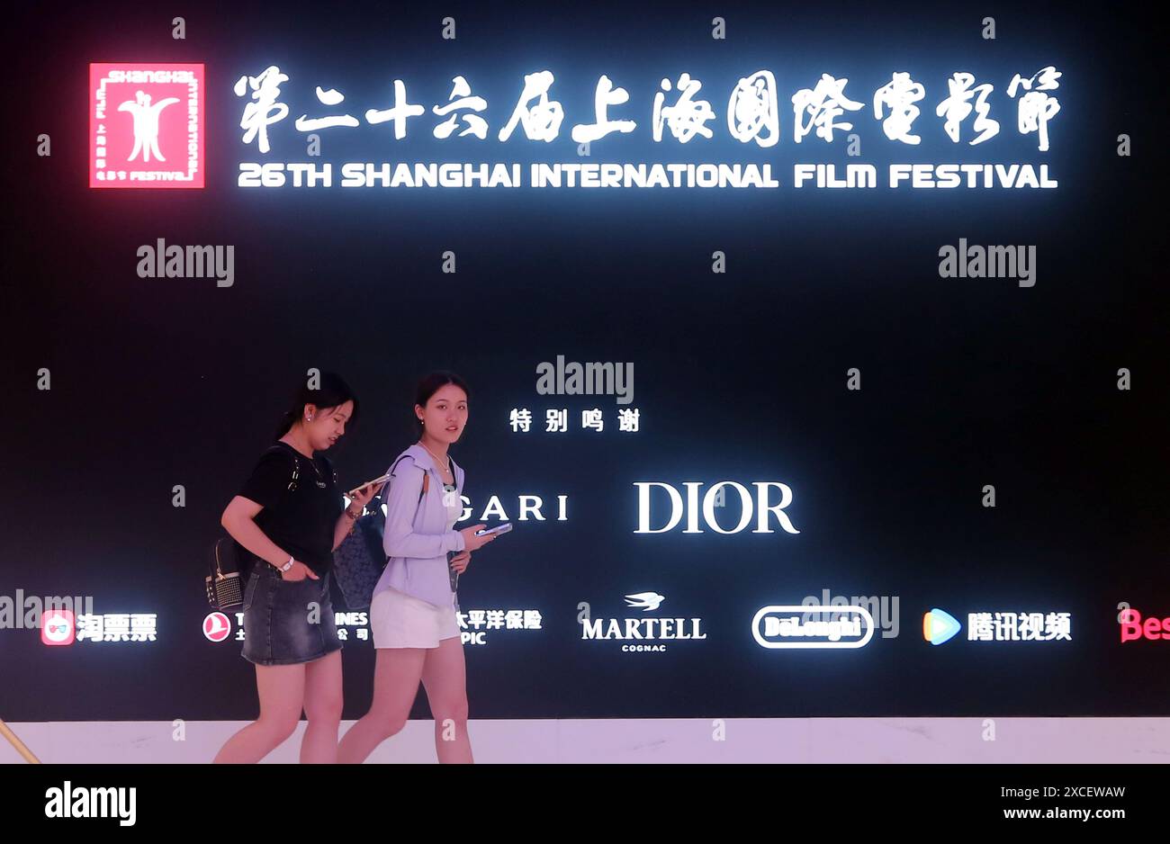 SHANGHAI, CINA - 15 GIUGNO 2024 - i fan del cinema passano un film promozionale dello Shanghai International Film Festival mostrato su un grande schermo a Shanghai Cine Foto Stock