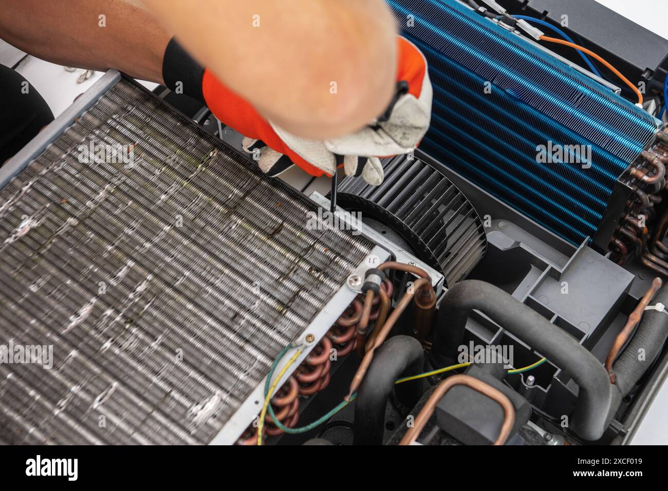 Tecnico degli elettrodomestici RV che lavora su un'unità di climatizzazione. Il tecnico utilizza un cacciavite per serrare una vite sull'unità. La ventola delle unità e. Foto Stock