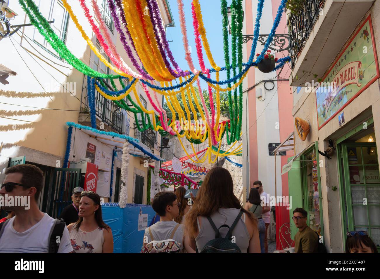 Persone che camminano per le strade di Alfama durante i popolari festeggiamenti dei Santi a Lisbona, in Portogallo, con tipiche decorazioni colorate di strada Foto Stock
