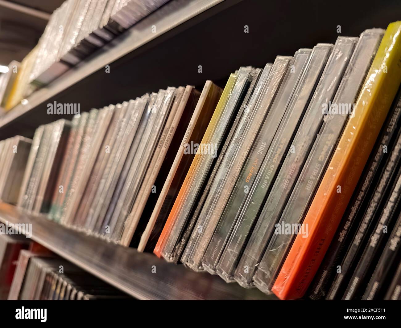 Una fila di diversi CD musicali su uno scaffale in un negozio, primo piano, nessuno, DOF poco profondo. Acquisto e vendita legale di album musicali, CD song album distr Foto Stock