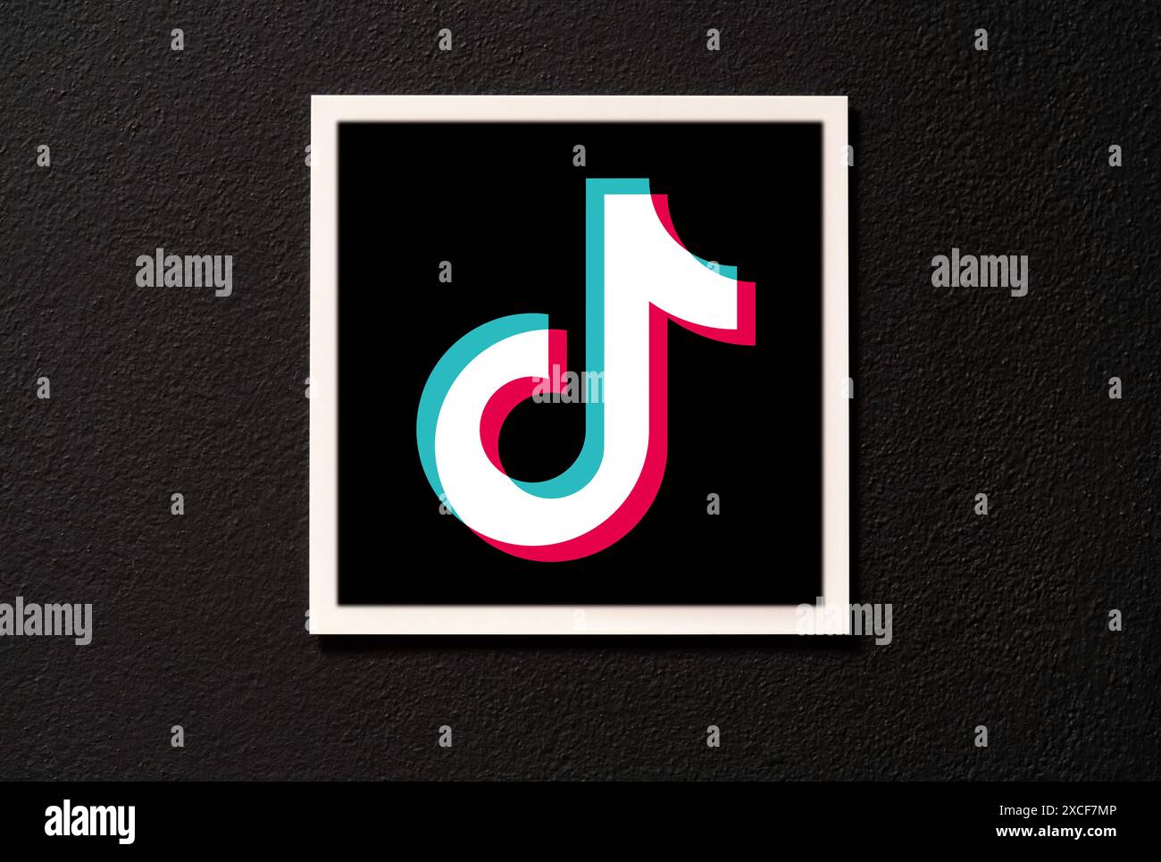 Logo dell'app ByteDance TikTok cartellino quadrato appeso su una parete scura, vista frontale, primo piano, nessuno. Tik Tok tendenze segnaletica di zona, logo dell'azienda del marchio nota Foto Stock