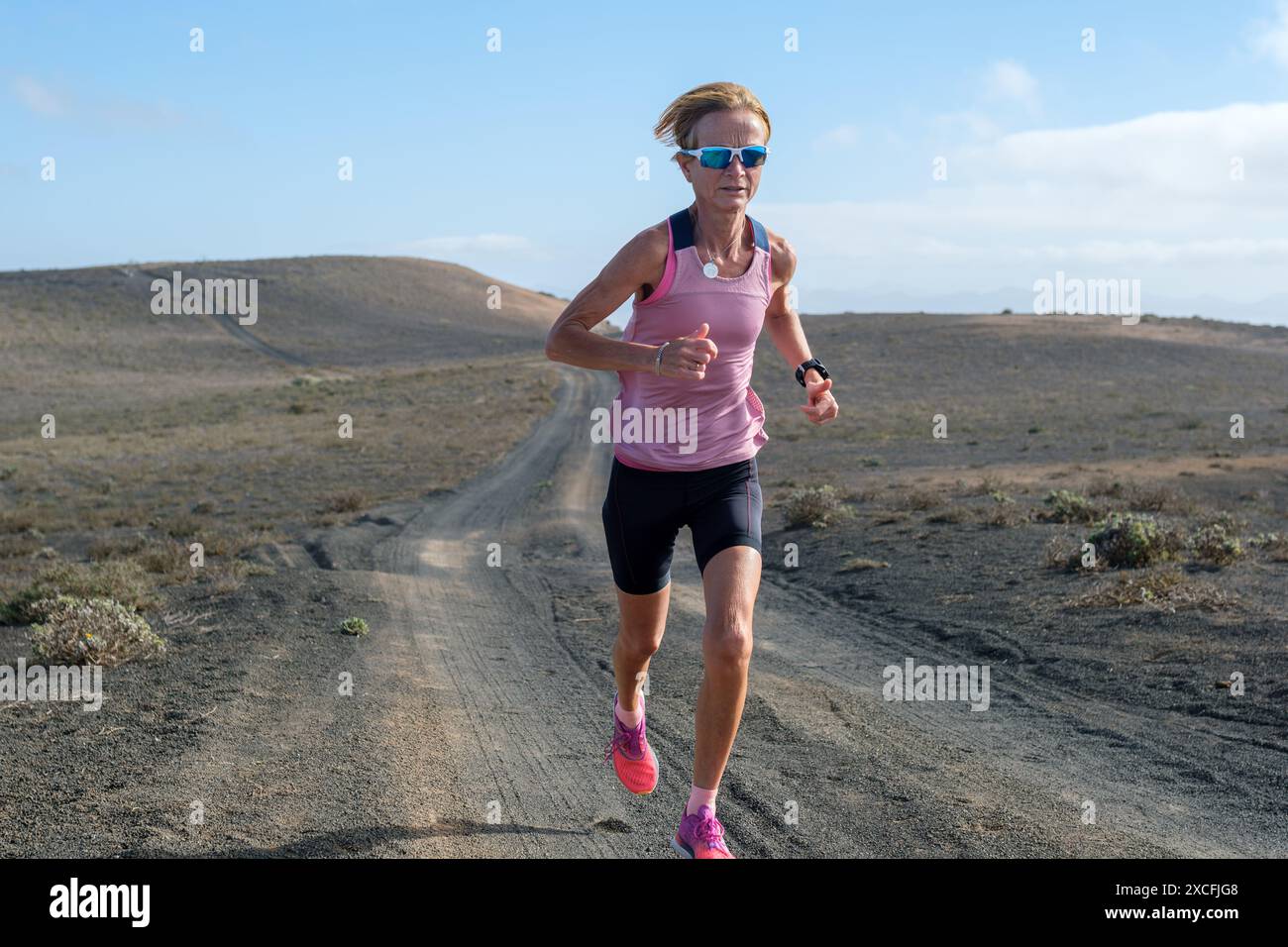 Donna appassionata di fitness che corre su una pista polverosa in una vasta area desolata. Foto Stock