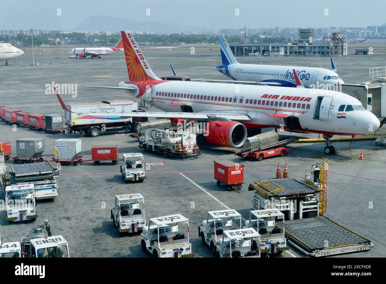 Planes of Air India e Indigo sull'asfalto dell'Aeroporto Internazionale Chhatrapati Shivaji Maharaj di Mumbai, India, circondato da veicoli di servizio Foto Stock