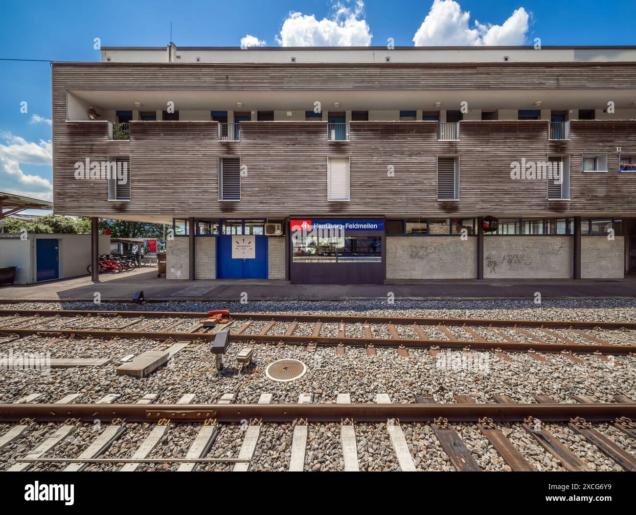 Herrliberg Feldmeilen, Svizzera - 13 giugno 2024: Moderna stazione ferroviaria di Herrliberg Feldmeilen con lastre di legno, grandi finestre, giorno di sole. Foto Stock