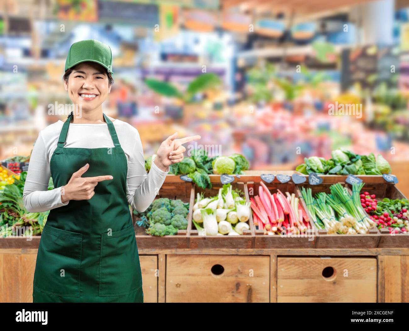 I venditori asiatici indossano grembiule verde e berretto verde sorridenti sul mercato Foto Stock