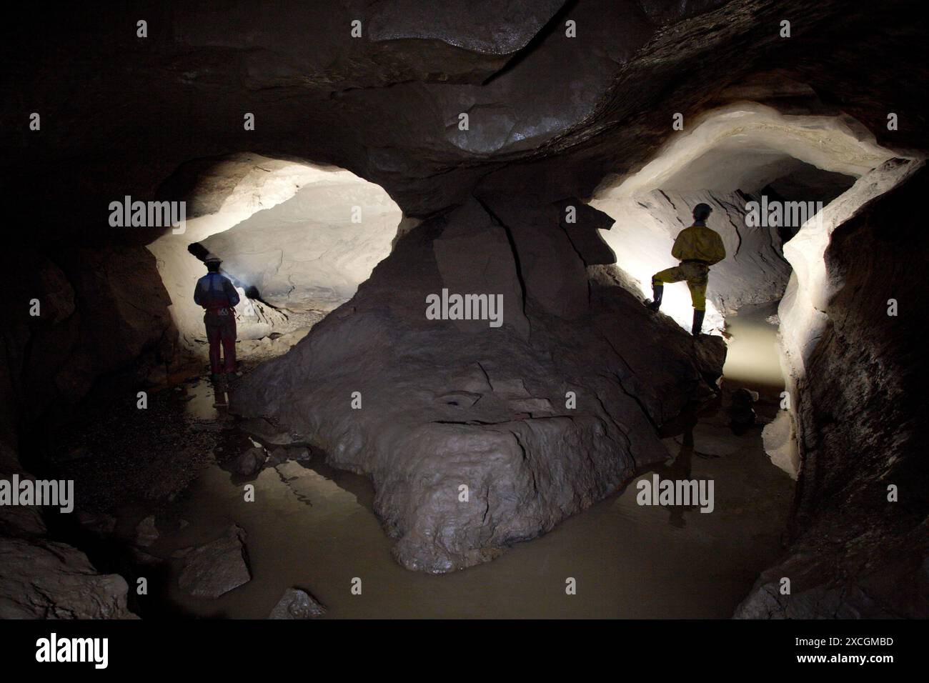 Due esploratori delle grotte illuminano un passaggio immagine speculare nel profondo sottosuolo di una grotta in Inghilterra. Foto Stock