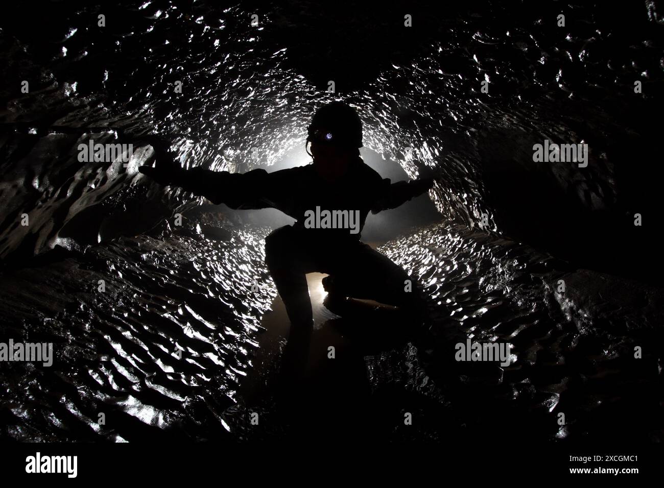 Cave explorer posa per la fotografia in un passaggio ben formato nel Derbyshire in Inghilterra. Foto Stock