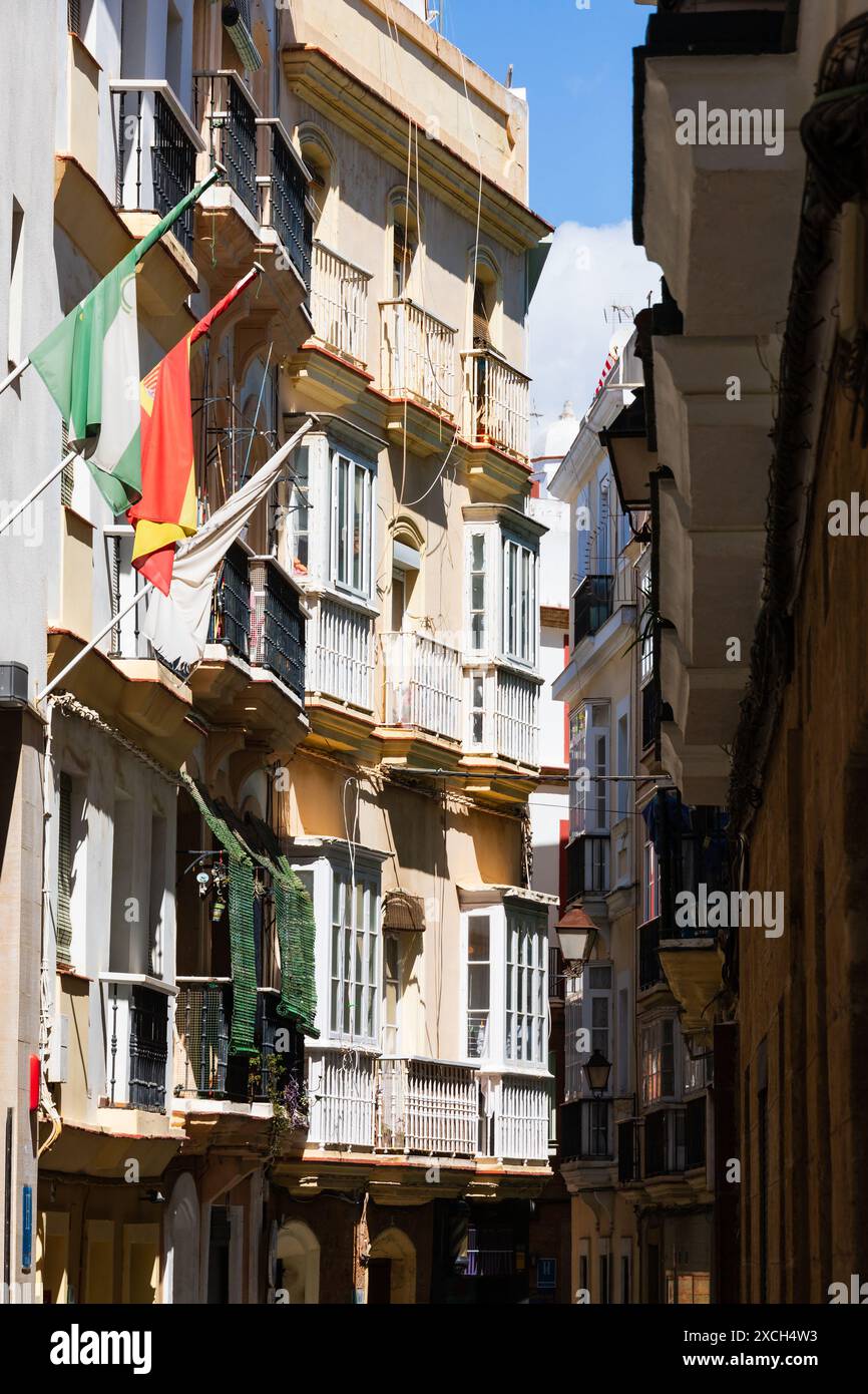 Case con balconi che battono bandiere nelle strade secondarie di Cadice, Andalusia, Spagna Foto Stock