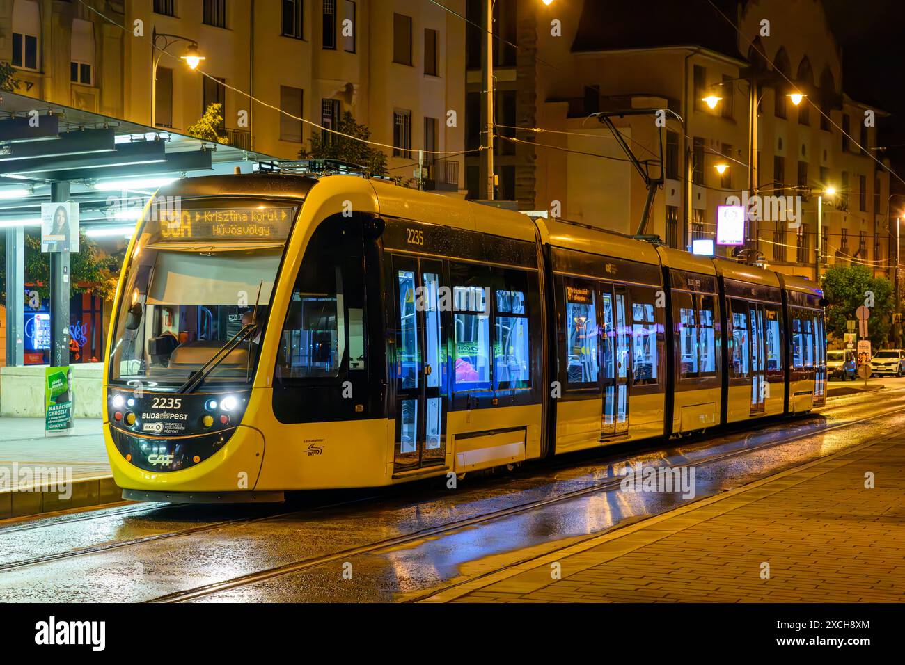 Un tram CAF Urbos 3 in una serata piovosa di notte a Budapest, Ungheria Foto Stock