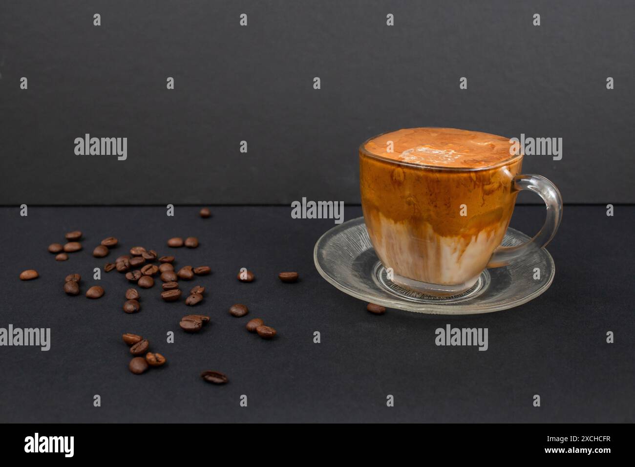 Caffè dalgona fatto in casa con chicchi di caffè sparsi su nero Foto Stock