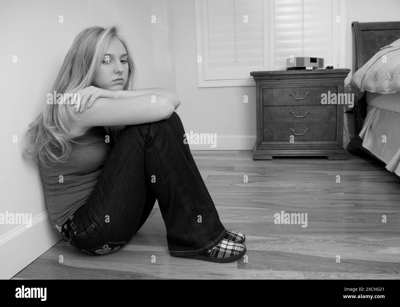 Depressa ragazza caucasica seduta sul pavimento della camera da letto. STATI UNITI Foto Stock