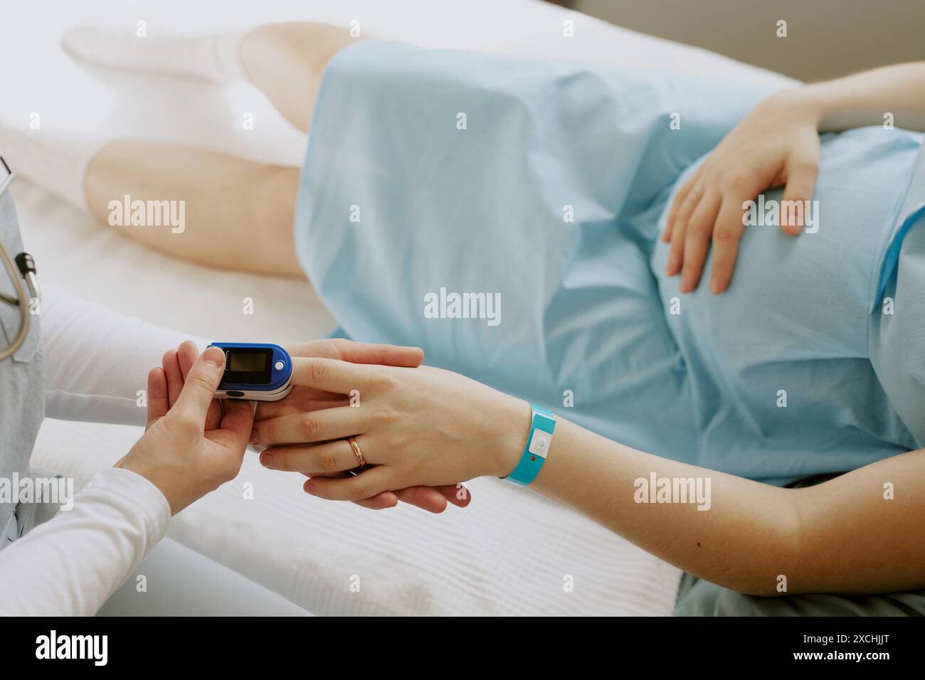 Infermiera che tiene per mano le pazienti in gravidanza ed esamina la saturazione con l'ausilio del pulsossimetro Foto Stock