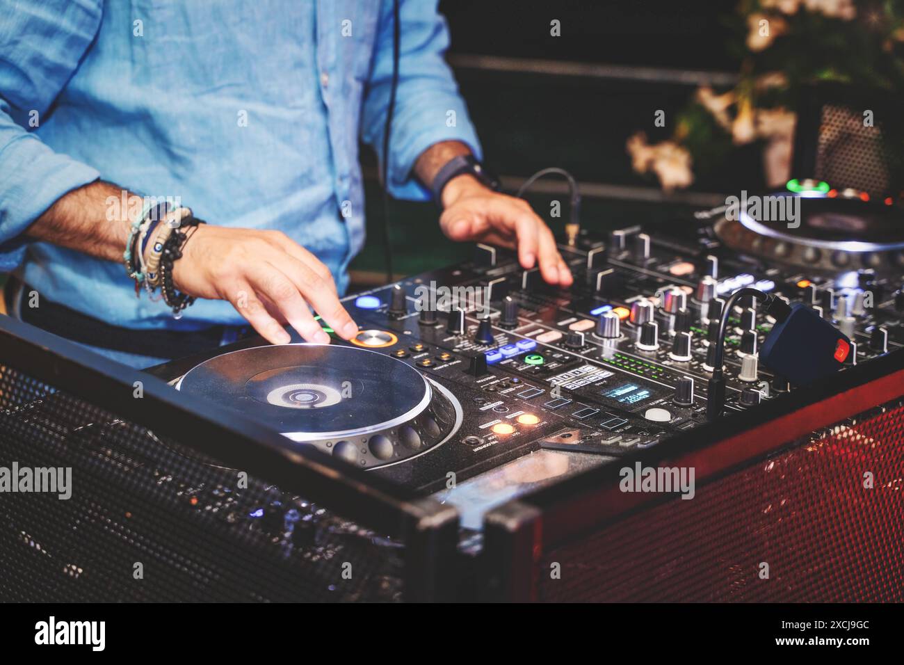 Un DJ che mescola musica su attrezzature da DJ professionali, mostrando una vivace ed energica vita notturna. Ideale per musica, eventi e contenuti di intrattenimento. Foto Stock