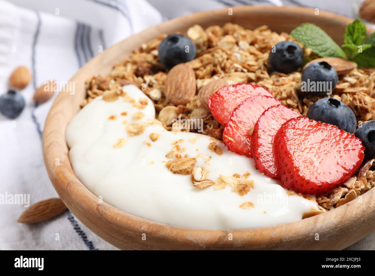 Gustose muesli con frutti di bosco, mandorle e yogurt nel recipiente sul tavolo, primo piano Foto Stock