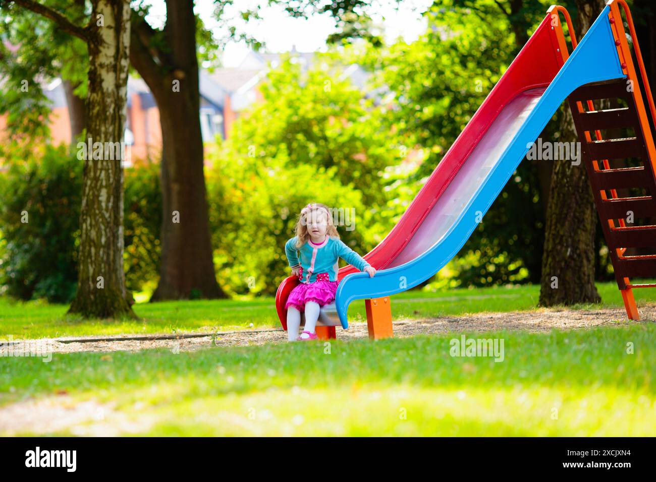 I bambini esplorano la natura. I bambini giocano nel parco soleggiato. Bambini nel parco giochi dello splendido parco estivo. Divertimento all'aperto per tutta la famiglia. Ragazzino su swing e scivolo. Foto Stock