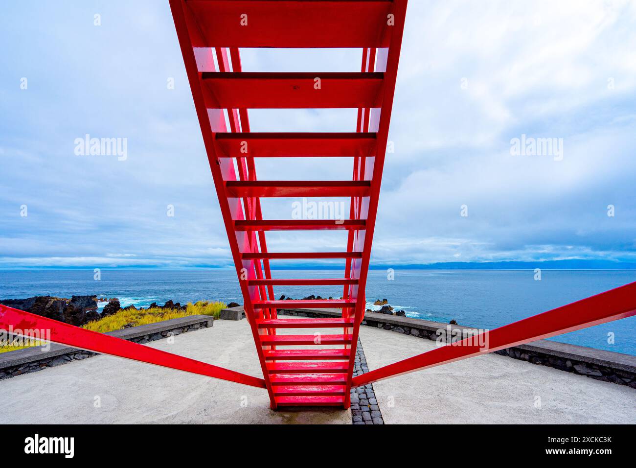 Scale rosse in primo piano con cornice simmetrica sotto lo sfondo blu nuvoloso del cielo, colori contrastanti Foto Stock