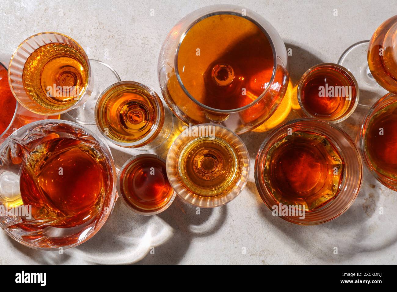 Diversi deliziosi liquori in bicchieri su tavolo grigio chiaro, piatto Foto Stock