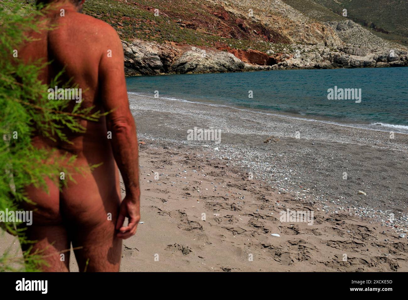 Uomo nudo sulla spiaggia greca, Isole del Dodecaneso, Grecia. Ho preso i miei 2024 Foto Stock