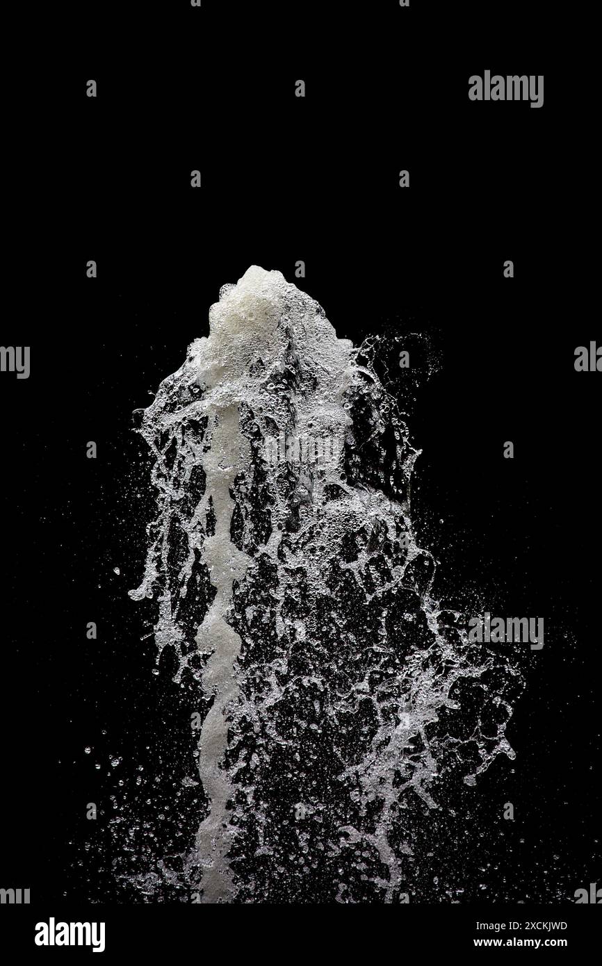 L'acqua esplode nell'aria con uno sfondo nero, verticale Foto Stock